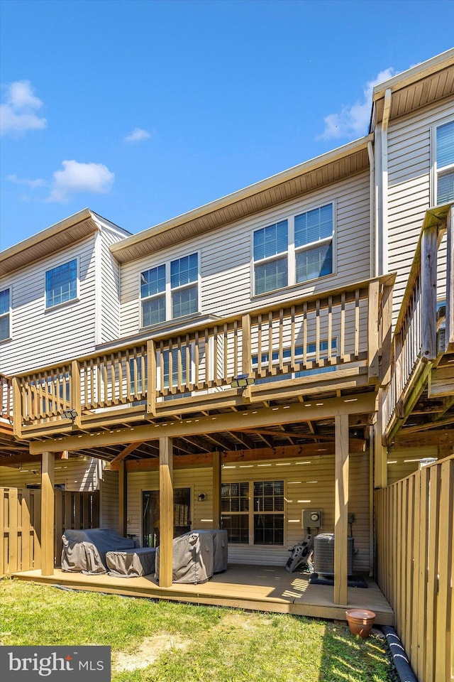 rear view of house with a wooden deck, central AC unit, and fence