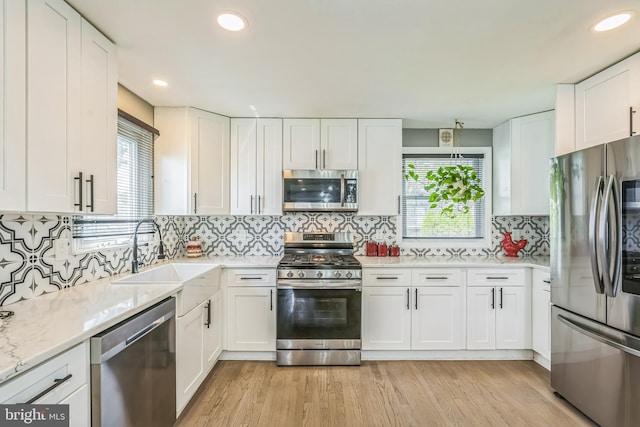 kitchen featuring white cabinetry, appliances with stainless steel finishes, a sink, and light wood finished floors