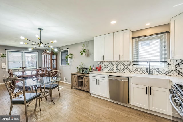 kitchen with an inviting chandelier, light countertops, a sink, light wood finished floors, and stainless steel appliances