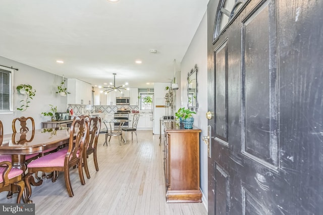 dining space with recessed lighting, light wood-style flooring, and a notable chandelier