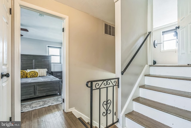 stairway with baseboards, hardwood / wood-style floors, and visible vents