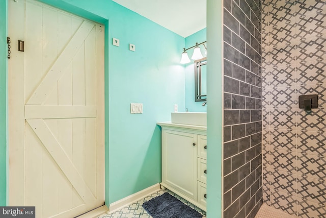 full bathroom with vanity, baseboards, and a tile shower