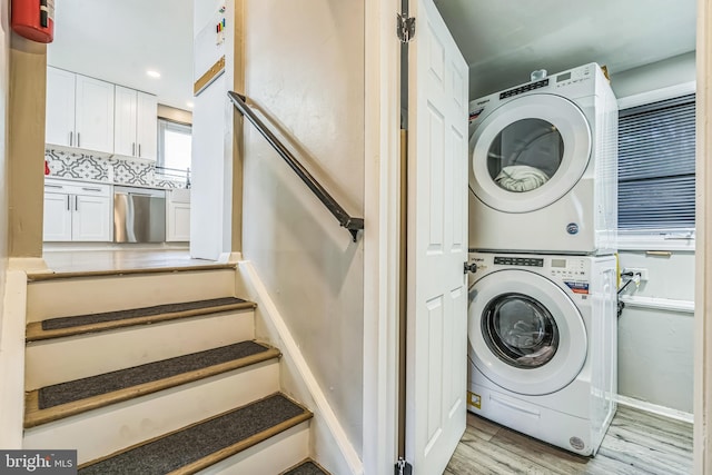 washroom with stacked washer and clothes dryer, light wood-style flooring, and laundry area