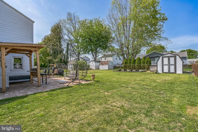 view of yard featuring a patio, a fenced backyard, a shed, and an outbuilding