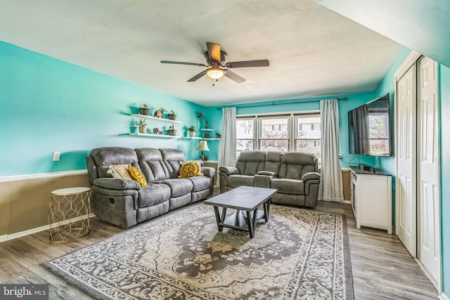 living room featuring baseboards, ceiling fan, and wood finished floors