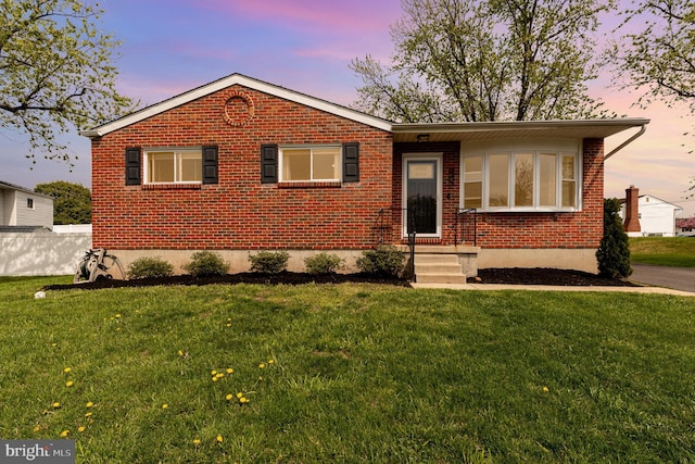 single story home featuring a yard and brick siding