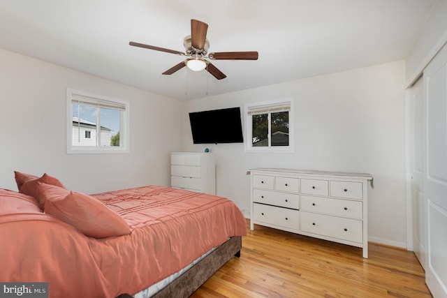 bedroom featuring a closet, baseboards, light wood-type flooring, and a ceiling fan
