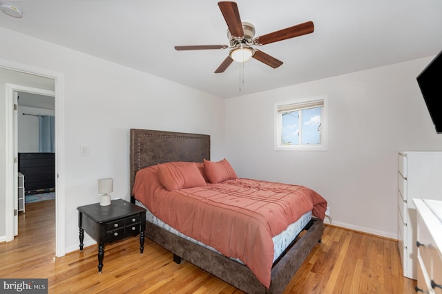 bedroom with light wood finished floors, baseboards, and a ceiling fan