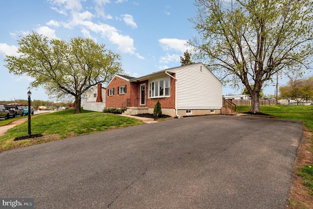 view of front of property with brick siding, a front lawn, fence, and a chimney