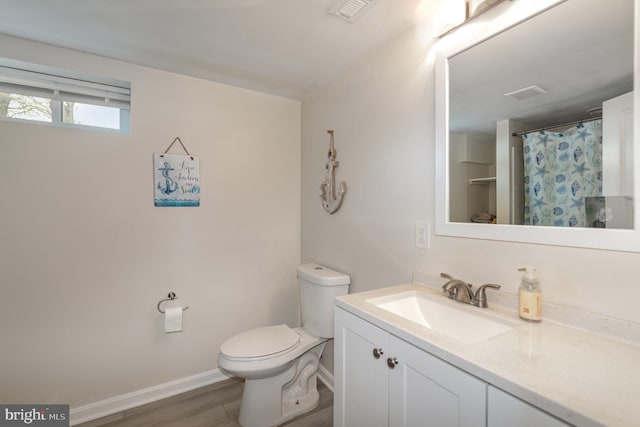 bathroom with visible vents, baseboards, toilet, vanity, and wood finished floors