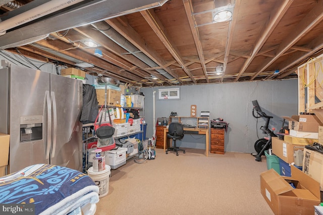 unfinished basement featuring carpet floors and stainless steel fridge