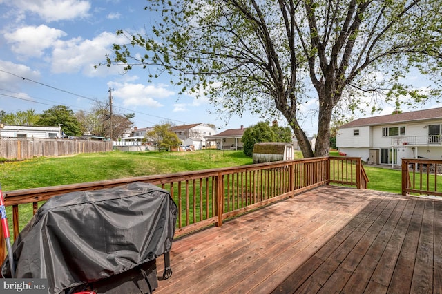 wooden deck featuring an outbuilding, grilling area, fence, and a yard