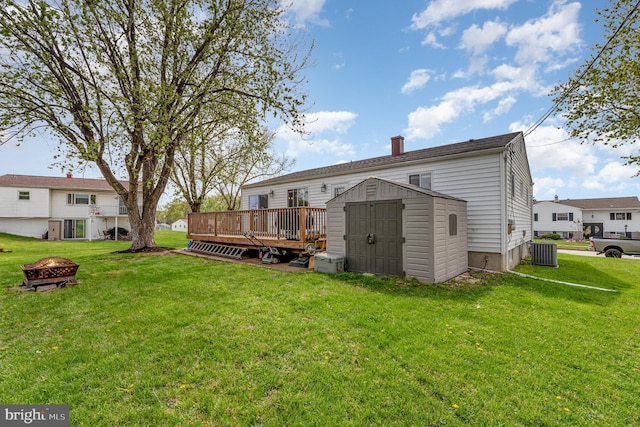 back of house featuring a wooden deck, an outdoor structure, an outdoor fire pit, a storage unit, and central AC unit