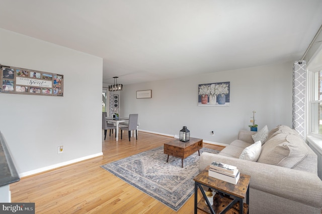 living room with baseboards, an inviting chandelier, and wood finished floors