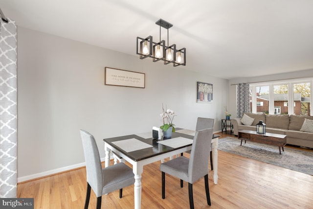 dining area with baseboards, a notable chandelier, and light wood-style floors