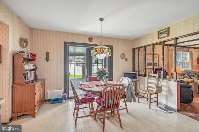 dining room featuring wallpapered walls and light flooring
