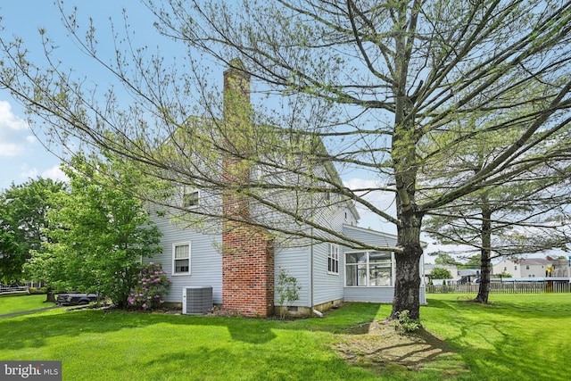 view of home's exterior featuring cooling unit, a chimney, and a sunroom
