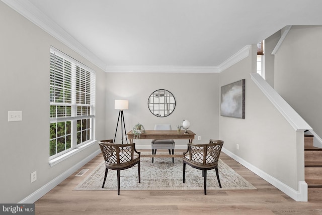 office space with crown molding, baseboards, visible vents, and light wood-style floors