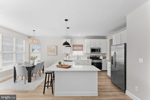 kitchen with a sink, baseboards, appliances with stainless steel finishes, and white cabinetry