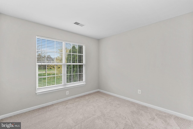 unfurnished room with carpet flooring, visible vents, and baseboards