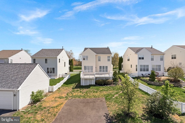 rear view of house with a yard, a fenced backyard, a deck, and a residential view