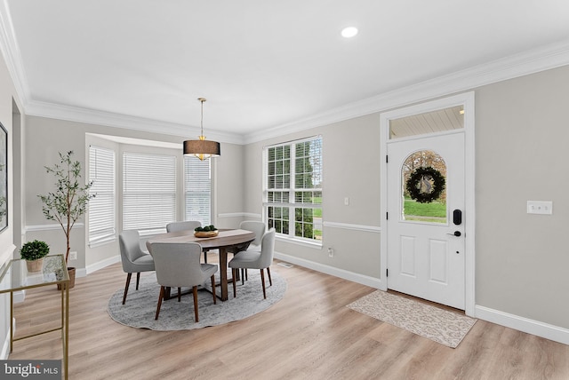 dining space with ornamental molding, baseboards, and light wood finished floors