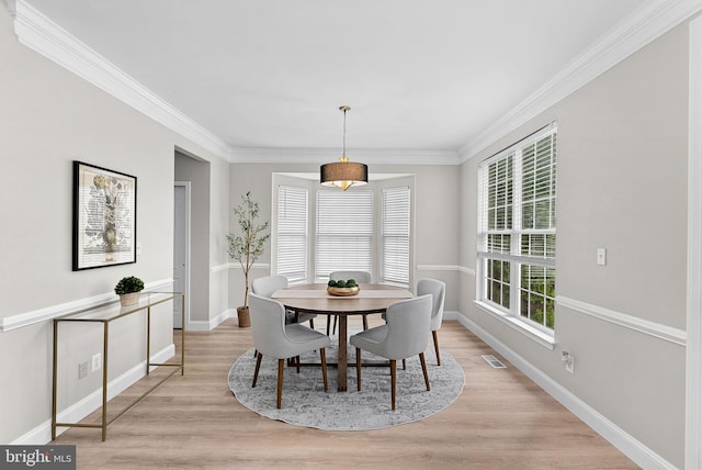 dining room featuring ornamental molding, visible vents, light wood-style flooring, and baseboards