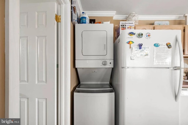 laundry area with crown molding, stacked washer and dryer, and laundry area
