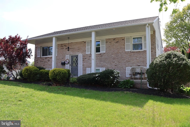 raised ranch featuring brick siding and a front yard
