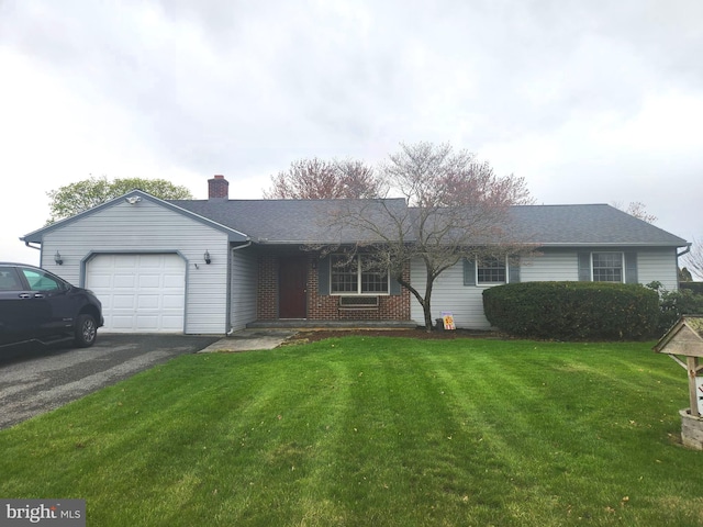 ranch-style house featuring an attached garage, a chimney, brick siding, a front lawn, and driveway