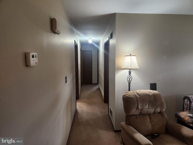 hallway with visible vents, light colored carpet, and baseboards
