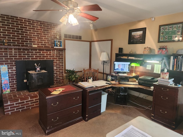 office space featuring a wood stove, carpet flooring, visible vents, and a ceiling fan