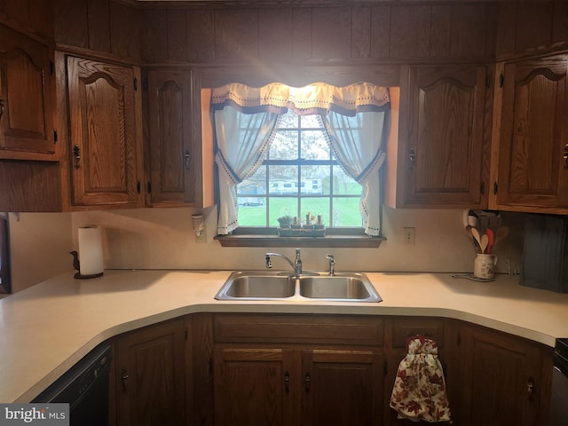 kitchen featuring light countertops, black dishwasher, and a sink