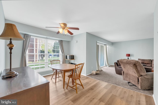 dining area with ceiling fan, light wood-style flooring, and baseboards