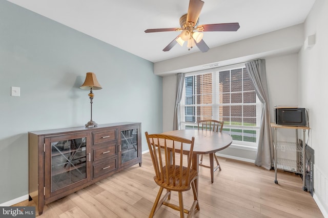 dining room featuring ceiling fan, baseboards, and light wood-style floors