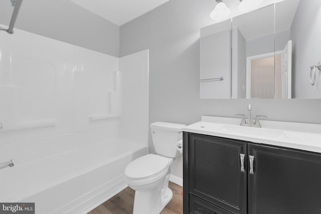 full bath featuring toilet, wood finished floors, vanity, baseboards, and bathtub / shower combination