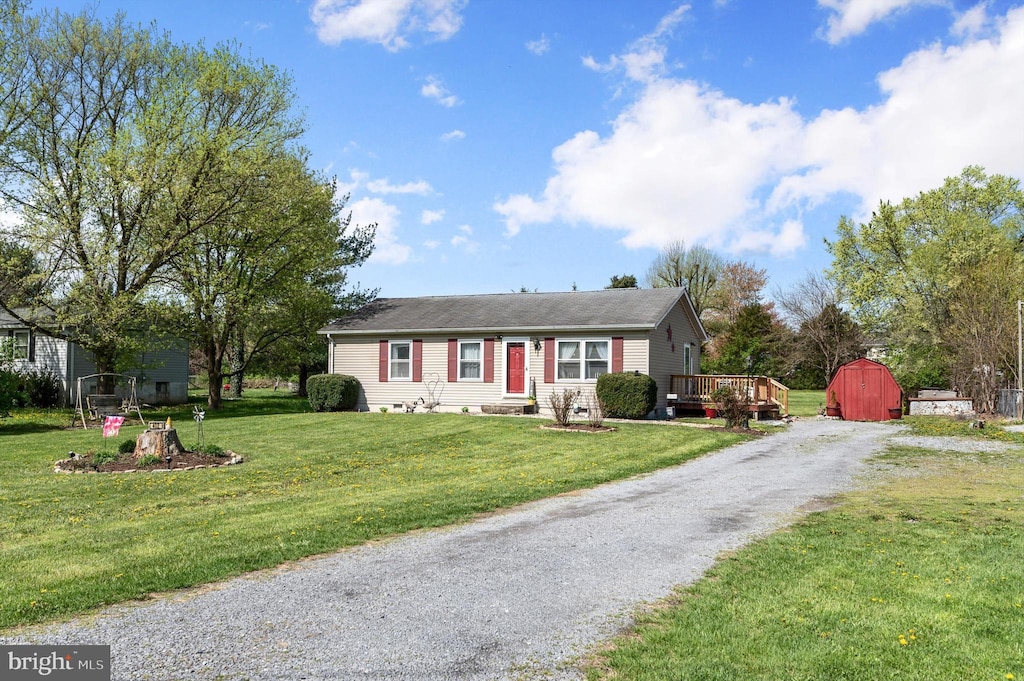 ranch-style home featuring gravel driveway, a storage shed, an outbuilding, and a front lawn