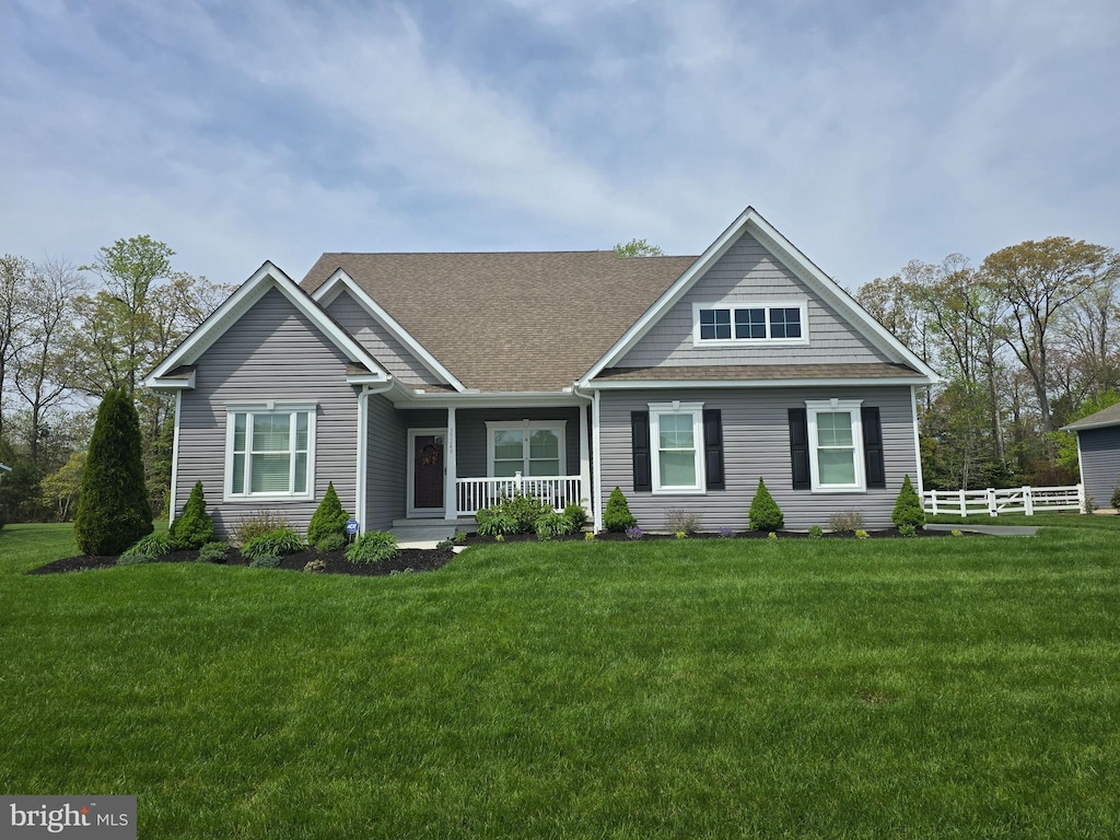 view of front of property with fence, a porch, a shingled roof, and a front yard