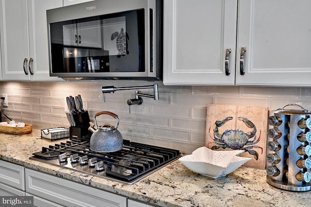 room details with light stone counters, white cabinetry, appliances with stainless steel finishes, and tasteful backsplash