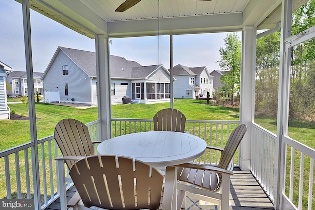 sunroom / solarium featuring a residential view, ceiling fan, and a wealth of natural light