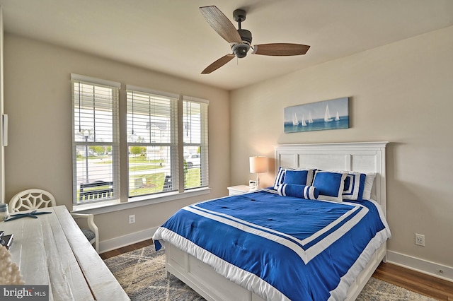 bedroom with baseboards, multiple windows, dark wood-style floors, and ceiling fan