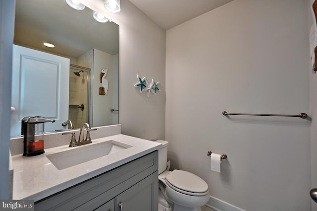 bathroom featuring vanity, a shower with door, baseboards, and toilet