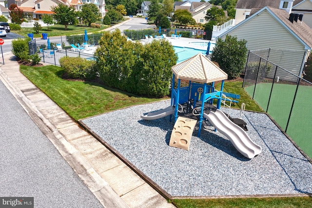 view of playground with fence, a yard, and a residential view