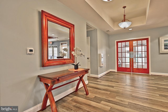 entrance foyer featuring french doors, visible vents, wood finished floors, baseboards, and a raised ceiling