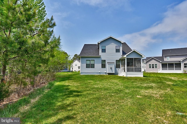rear view of house featuring a sunroom and a yard