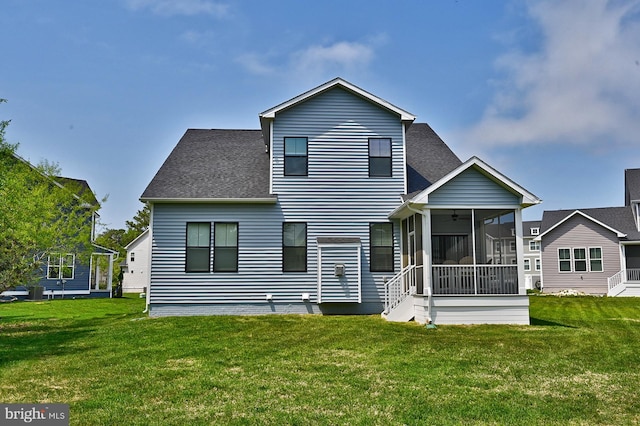 back of property with a sunroom, a ceiling fan, roof with shingles, and a yard