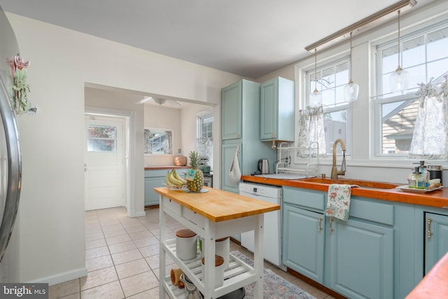 kitchen featuring a sink, plenty of natural light, blue cabinets, wooden counters, and dishwasher