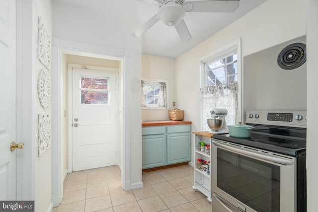 kitchen featuring a ceiling fan, wood counters, stainless steel range with electric cooktop, light tile patterned floors, and baseboards