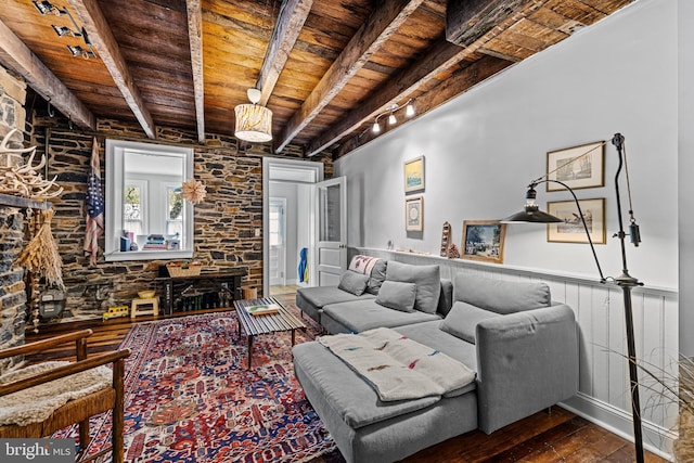 living area with rail lighting, hardwood / wood-style floors, a wainscoted wall, wooden ceiling, and beam ceiling