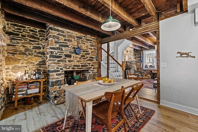 dining room with wood finished floors, beamed ceiling, baseboards, wood ceiling, and stairs